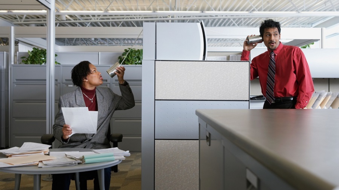 Two office workers using a tin can telephone